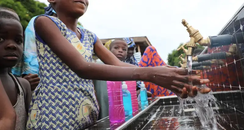 Residents of an informal settlement in Tamale, northern Ghana, receive clean water through hand washing stations and water tanks as a result of a project led by UN-Habitat, delivered 27 July 2021, to increase their ability to fight Covid-19.